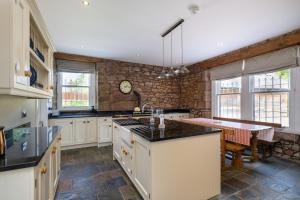 a kitchen with white cabinets and a stone wall at Drumnacree House, Alyth in Alyth