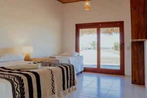 two beds in a room with a view of the beach at Echoes Surf Casitas in Mechapa