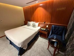 a hotel room with a bed and a blue chair at فندق تمكين-TamkeenHotel- تابع لعلامة كلاديوم- A Cladium brand in Medina