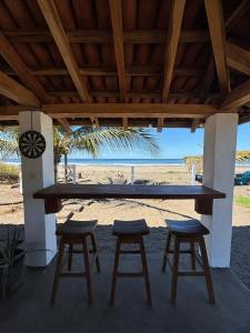 a table and stools under a pavilion with the beach at Echoes Surf Casitas in Mechapa +22 photos