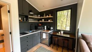 a kitchen with black cabinets and a sink and a window at Bison Farm - Cabin "Cielo" in Culpeper +33 photos