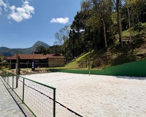 a tennis court with a green fence and mountains in the background at Casa 05 Vale Boa Vista - Refúgio Moderno em Condomínio Exclusivo in Teresópolis +30 photos