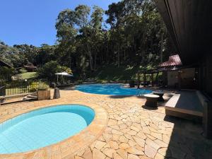 a swimming pool in a yard with a patio and a house at Casa 05 Vale Boa Vista - Refúgio Moderno em Condomínio Exclusivo in Teresópolis
