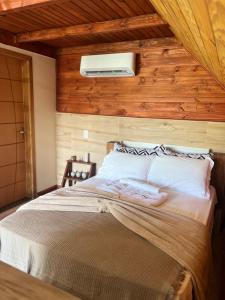 a bedroom with a bed with a wooden wall at Refúgio do Lago in Fraiburgo