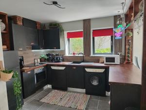 a kitchen with black cabinets and a sink and a dishwasher at the ring of kerry riverside apartment in Killorglin