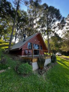 a small cabin with a porch in the grass at Refúgio do Lago in Fraiburgo
