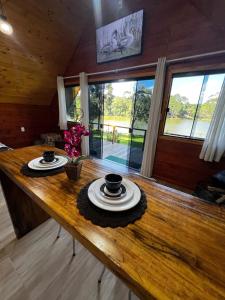 a wooden table with two cups and plates on it at Refúgio do Lago in Fraiburgo