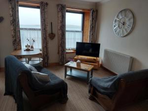 a living room with a couch and a tv and a table at Bellevue Inn in Saint Margarets Hope