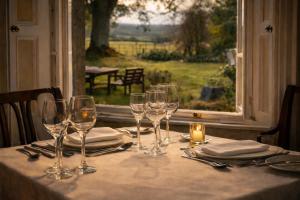 a table with wine glasses on a table with a window at Nent Hall Country House Hotel in Nenthead