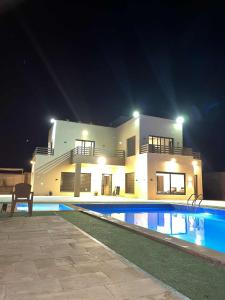 a large house with a swimming pool at night at Green view in Al Mazār