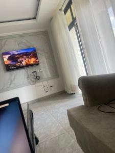a living room with a couch and a tv on the wall at Kigali Clever stay Villaa in Kigali