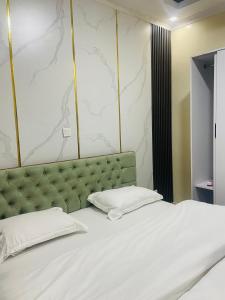 a bedroom with a white bed with a green headboard at Kigali Clever stay Villaa in Kigali
