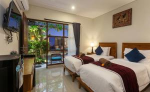 a hotel room with two beds and a balcony at Naksa Homestay Sanur in Sanur +13 photos