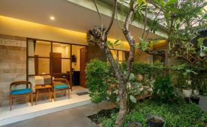 a room with a table and chairs and a tree at Naksa Homestay Sanur in Sanur
