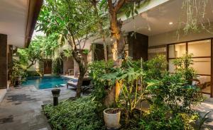 a house with a pool and trees and plants at Naksa Homestay Sanur in Sanur