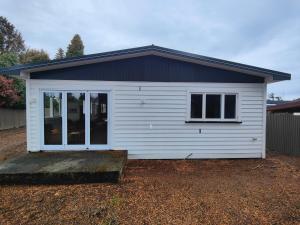 a small white garage with a window on it at Arrive and Revive Te Anau in Te Anau