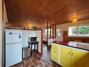 a kitchen with yellow cabinets and a white refrigerator at Arrive and Revive Te Anau in Te Anau