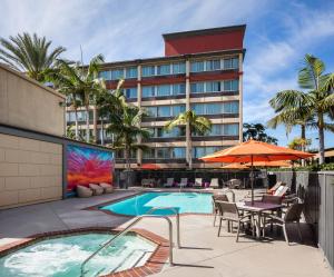 ein Hotel mit Pool, Tischen, Stühlen und einem Sonnenschirm in der Unterkunft ALO Hotel by Ayres, Orange in Anaheim