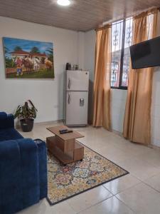 a living room with a blue couch and a refrigerator at Los Arrieros - Hospedaje Rural in Manizales +16 photos