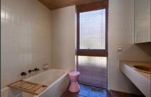 a bathroom with a tub and a window and a sink at Retro Reservoir Retreat in Kennington