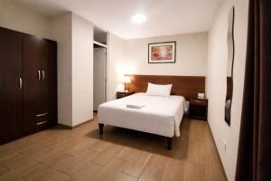 a bedroom with a white bed and a wooden floor at El Solar Inn in Arequipa