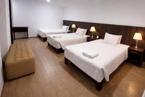 a hotel room with two beds and a chair at El Solar Inn in Arequipa
