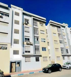 two tall buildings with cars parked in front of them at Swiss Home in Agadir