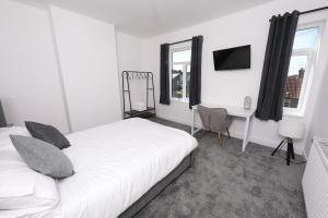 a white bedroom with a bed and a desk and window at Spacious 6-Guest Retreat with Pool Table in Dinnington