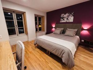 a bedroom with a large bed with purple walls at Auberge de l'Etoile in Vignory