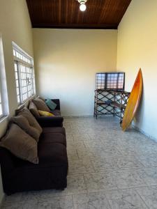 a living room with a couch and a surfboard on the wall at Casa do Sapê 5 dormitórios em Ubatuba in Ubatuba