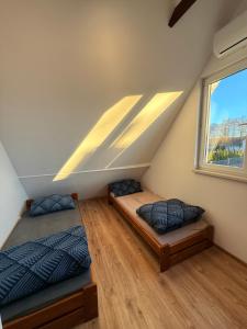 two beds in a attic room with a window at Zakątek Lechicki Domek in Tarnów Jezierny
