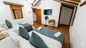 a room with two beds and a couch and a tv at Hotel Boutique Cenit in Villa de Leyva