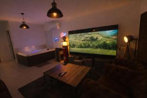 a living room with a large flat screen tv at Jacuzzi et cinéma privatif P1 in Pessac +1 photo