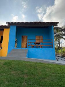 a blue and yellow house with a table on it at Casa azul Recanto Doce Lar in Gravatá