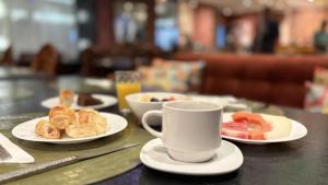 a table with plates of food and a cup of coffee at Hotel Transamerica Berrini in São Paulo