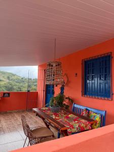 a table and chairs in a room with an orange wall at Casa Laranja Recanto Doce Lar in Gravatá