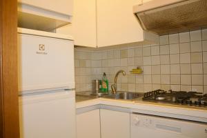 a kitchen with white cabinets and a sink and a stove at Iconic 3-BR Home Steps from Duomo in Milan