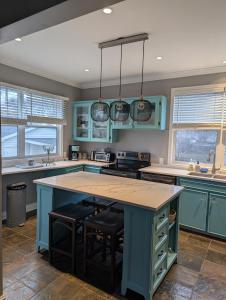 a kitchen with blue cabinets and a large island with stools at Charles Street Vacation Home in Lethbridge