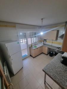 a kitchen with a white refrigerator and a white tile floor at Appartement de luxe in Sidi Daoud +6 photos