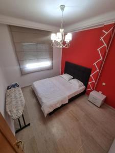 a bedroom with a bed and a red wall at Appartement de luxe in Sidi Daoud