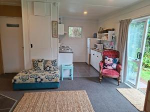 a living room with a chair and a kitchen at Bach on Waikawa 2 bedroom home in Picton