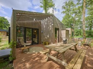 a wooden deck with a picnic table and bench at Cabin 22 in Zutendaal