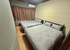 two beds in a small room with white sheets at HoTTOSTAY旭 in Nishi-biwajima