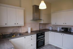 a kitchen with white cabinets and a sink and a stove at Two Perfect for large groups and secured free parking in Reading