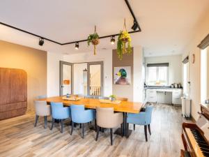 a kitchen and dining room with a wooden table and blue chairs at Villa Kaagervaaring in Kaag