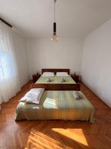 two beds in a white room with a wooden floor at Apartments by the sea Ugljan - 8264 in Ugljan