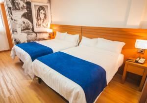 a hotel room with two beds with blue sheets at Hotel Jardin in San Cristóbal