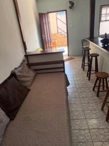 a couch sitting in a room with a kitchen at APARTAMENTO SIMPLES E ACONCHEGANTE in Paraty