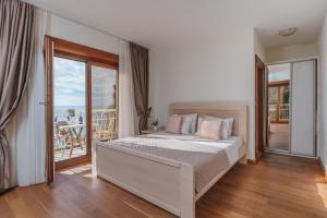 a white bedroom with a bed and a balcony at Apartments Pietra Mare in Petrovac na Moru +43 photos