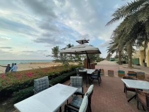 an outdoor patio with tables and chairs and an umbrella at كيان ايقونة الشاطئ ｋａｙａｎ in King Abdullah Economic City